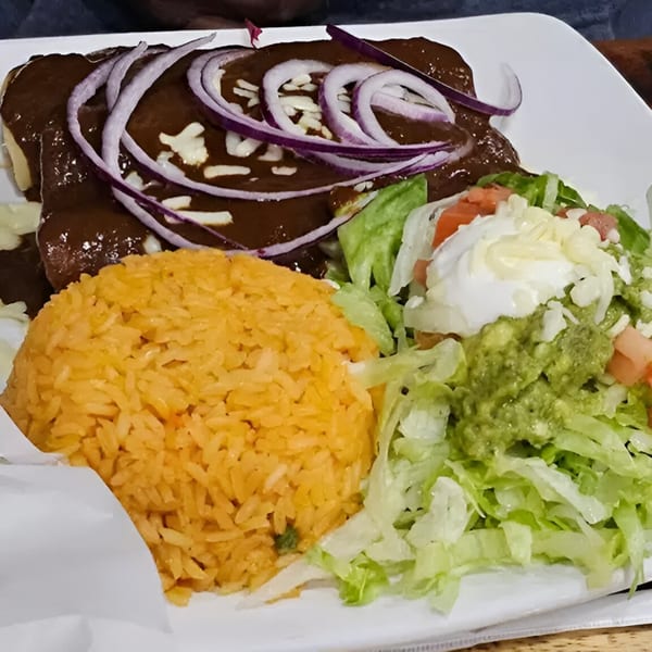 Mas Chingon Mexican Grill and Bar's enchiladas with mole sauce, rice, and a side salad.